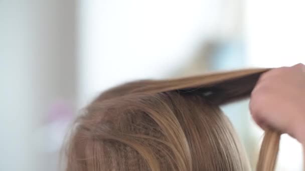 Het kapperswerk thuis. Scheidende strengen van blond haar en haarspeld. — Stockvideo