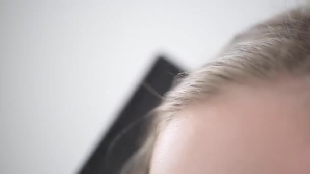 Szőke hajat fésülni a haj gyökerénél. A fésű fekete.. — Stock videók