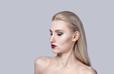 Çıplak omuzlu bir kadının parlak makyajı. Şık saç kesimi.