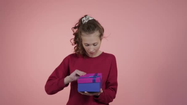 Una chica feliz abre un regalo en una caja brillante. Cumpleaños. . — Vídeo de stock