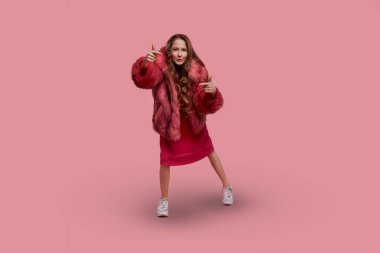 Moda kıyafetleri içinde neşeli kız model, açık pembe kürk manto.