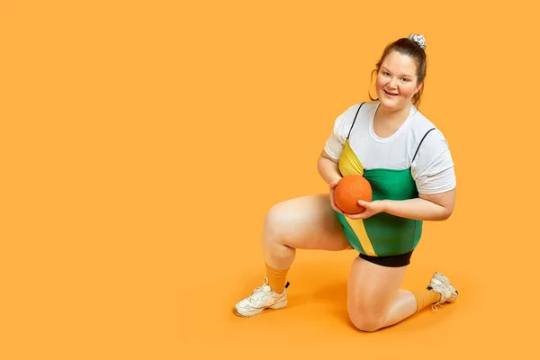 Bright fat girl is engaged in sports with a ball in her hands. A brunette girl.