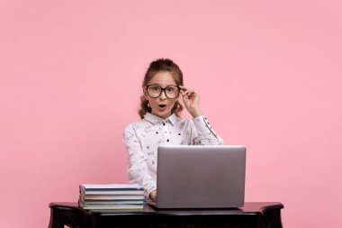 Güzel kız gözlük tutuyor. Masada dizüstü bilgisayarı olan bir kız..