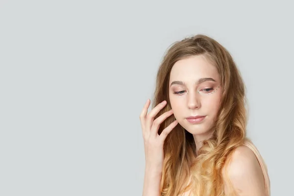 Una chica con el pelo largo y rubio sobre un fondo gris . —  Fotos de Stock