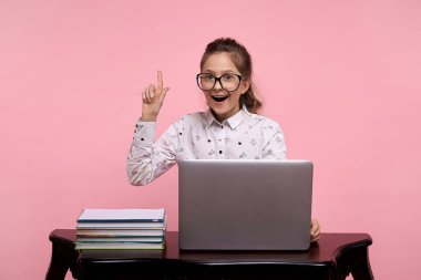 Kızın bir fikri var. Parmağını yukarı kaldır. Genç bir kız dizüstü bilgisayarın başında oturuyor.