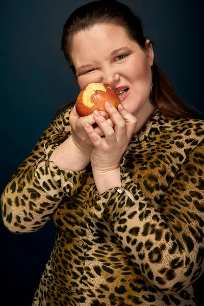 穿着漂亮豹衫的女孩吃苹果.体重超标. — 图库照片