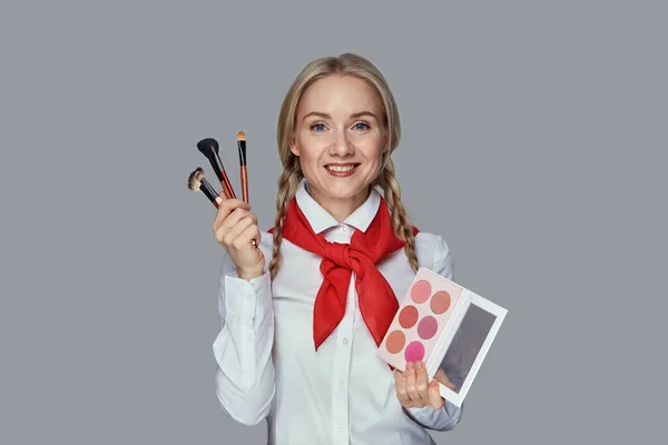 Chica feliz maquillaje artista con maquillaje en sus manos mira a la cámara — Foto de Stock