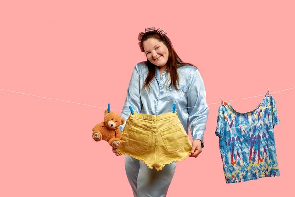 Alegre hermosa gorda chica en pijama sostiene lavado grandes pantalones cortos en sus manos y sonrisas . — Foto de Stock