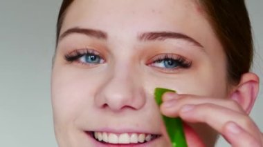 Genç kadın aloe vera yaprağı tutuyor.