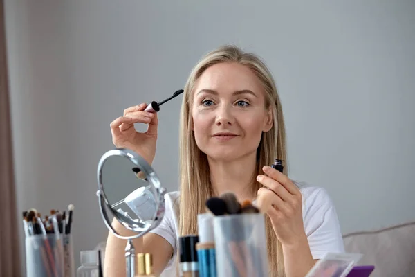 Een mooi meisje leert make-up thuis. Hoe wimpers goed te schilderen. — Stockfoto