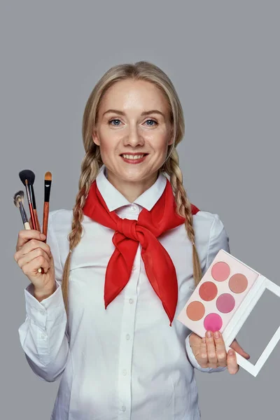 Chica con una paleta de sombras en sus manos. En la otra mano está el cepillo de maquillaje . —  Fotos de Stock