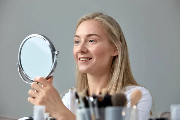 Een jonge vrouw maakt zich thuis op voor een ronde spiegel.. — Stockfoto