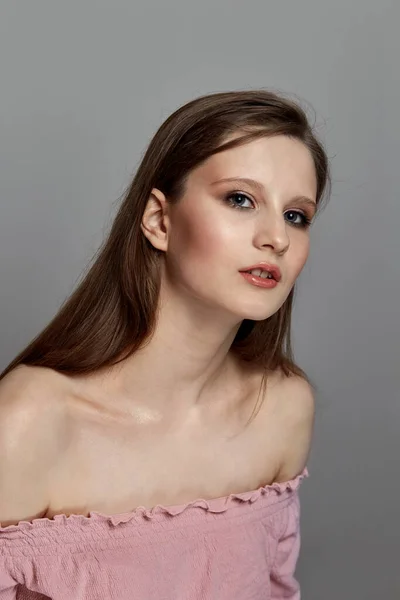 A menina morena olha para a câmera, vestido rosa e ombros abertos . — Fotografia de Stock