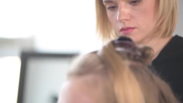 Створення зачісок у молодої дівчини з світлим волоссям . — стокове відео