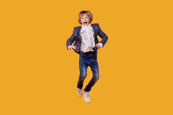 En pojke i vit skjorta och grå kostym i full tillväxt studsar och är i luften. — Stockfoto