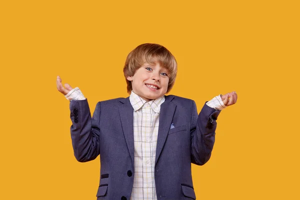 Leende pojke sträcker ut sina händer till sidorna och ställer en fråga — Stockfoto