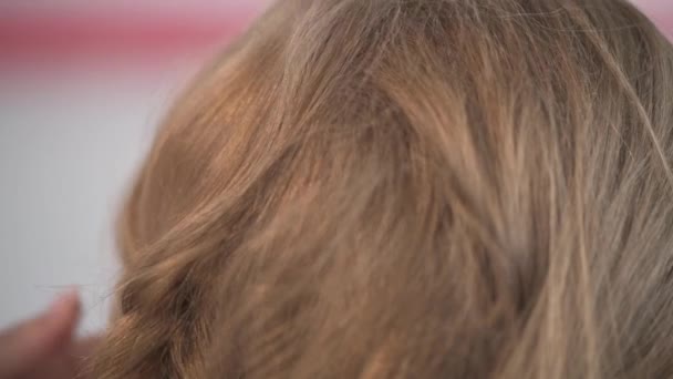 La creación de un peinado kárstico de una joven hermosa rubia . — Vídeo de stock