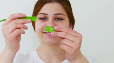 Kadının elinde aloe vera yaprağı parçaları var.