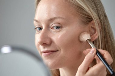 Yüzüne makyaj fırçası süren genç bir kızın kocaman yüzü..