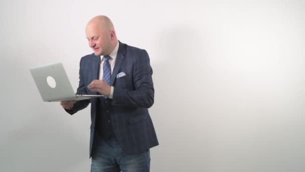 Bald joyful man with a laptop in hand looks at the laptop and waits for victory. — Stock Video