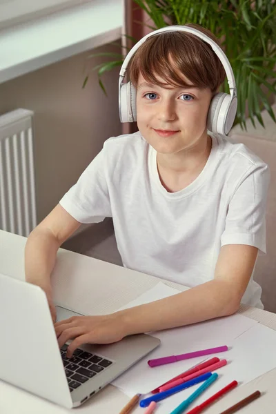 Bonito jovem está estudando em casa online com fones de ouvido na cabeça . — Fotografia de Stock