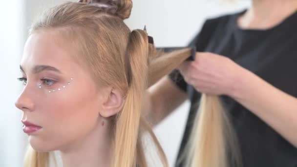 Het creëren van kapsels in een jong meisje met blond haar. — Stockvideo
