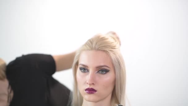 Fille blonde avec un maquillage lumineux dans le salon de beauté . — Video