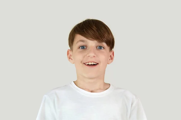 En stilig pojke med ett brett leende i en vit t-shirt. Mörkt hår. — Stockfoto