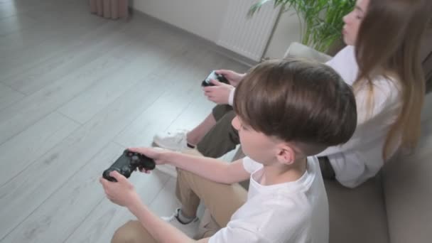 Brother and sister play with joysticks in their hands. — Stock Video