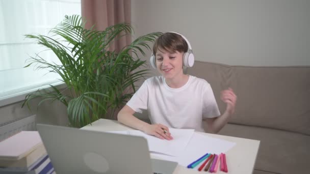 Smiling cheerful boy is looking at the laptop and chatting online with friends. — Stok Video