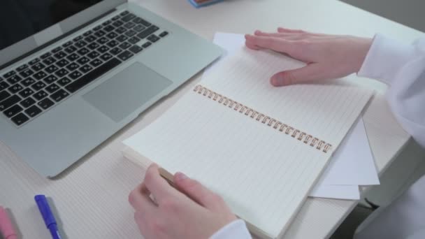 En la mesa frente a la chica hay un cuaderno en blanco y un portátil . — Vídeos de Stock