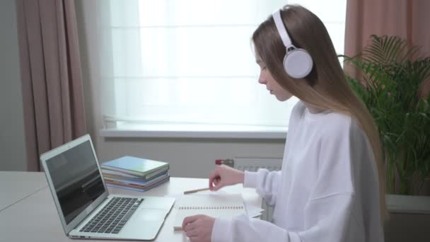 Belle petite écolière fille est engagée à la maison en ligne avec un ordinateur portable — Video