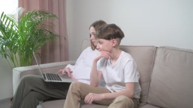 Erkek ve kız kardeş birlikte dizüstü bilgisayara ve çizgi filme bakıyor..