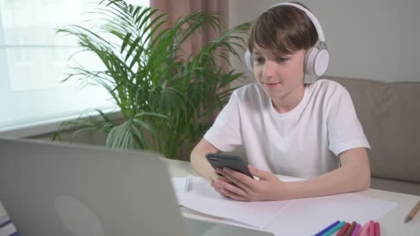 Egy vidám fiú pihen az iskolából, és telefonon játszik.. — Stock videók