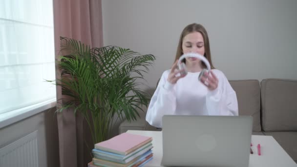 Uma linda garota é treinada em casa online com fones de ouvido na cabeça . — Vídeo de Stock