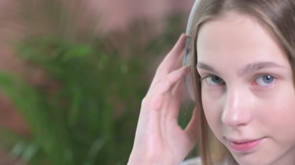 Közelkép egy fiatal gyönyörű lányról vezeték nélküli fülhallgatóban.. — Stock videók