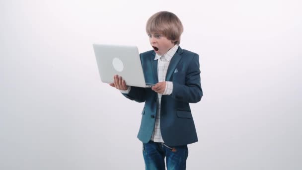 Gyönyörű aranyos szőke fiú néz meglepett a laptop, nyitott száj.