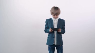 Beyaz tişörtlü bir çocuk cep telefonuyla oynar, kaybeder ve çok kızar..