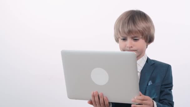 A handsome little businessman boy with a laptop in his hands gets angry, swears. — Stock Video