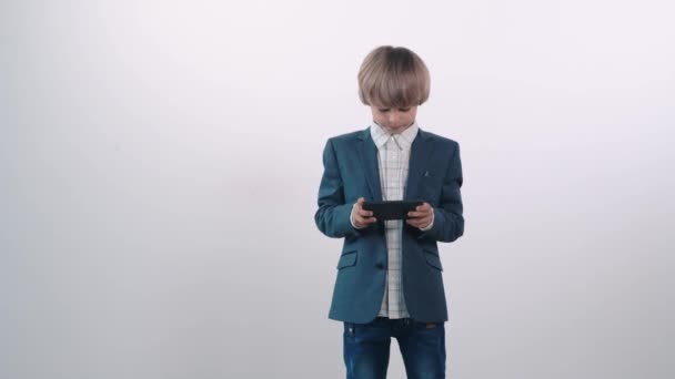 Un chico con una camisa blanca juega en un teléfono móvil, pierde y se enoja mucho . — Vídeos de Stock