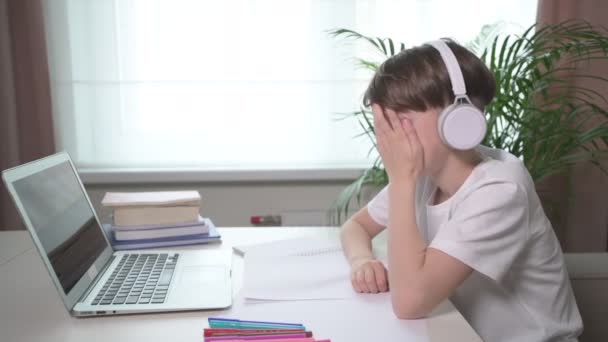 Túlhajszolt fiú ül egy kanapén egy laptopnál. Belefáradtam a tanulásba. — Stock videók