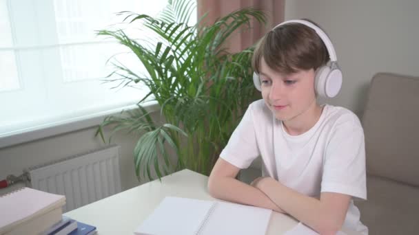 Un niño con auriculares está estudiando en línea en casa en una computadora portátil . — Vídeos de Stock