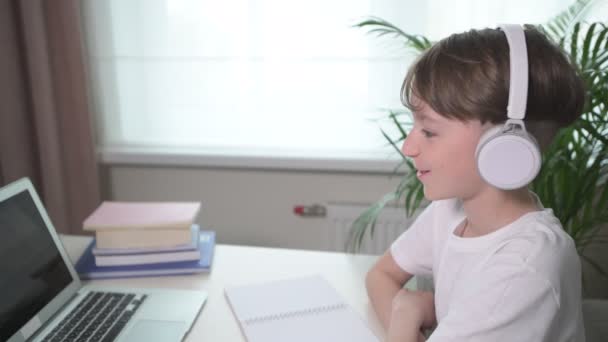 Pojken lyssnar uppmärksamt på föreläsningen i vita hörlurar. — Stockvideo