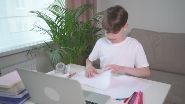 A fickó házi feladatot csinál, miközben az asztalnál ül. Ülök a kanapén.. — Stock videók