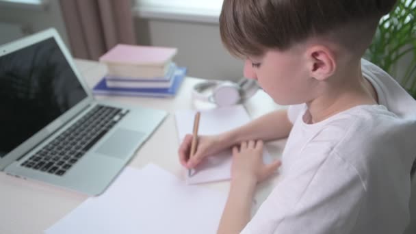 Mignon garçon écrit une conférence dans un carnet vide. Passer le cours en ligne . — Video