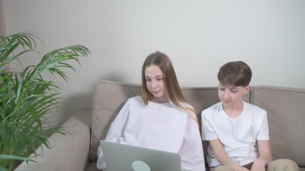 Broer en zus kijken samen naar een laptop en tekenfilms. — Stockvideo