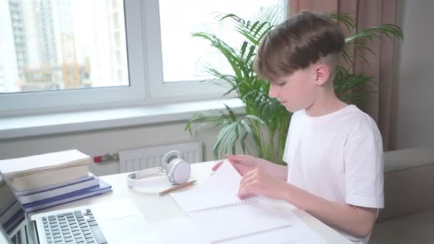 Joli garçon feuillette un cahier. Il fait ses devoirs. . — Video