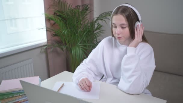 女の子は勉強の残りの部分を持っており、快適な穏やかな音楽に耳を傾ける. — ストック動画