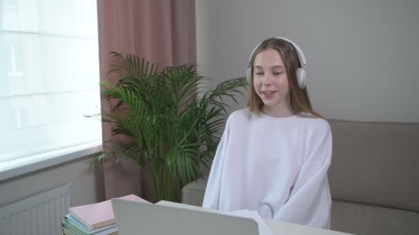 オンラインクラスでヘッドフォンで美しい若い女の子。家で学ぶ. — ストック動画