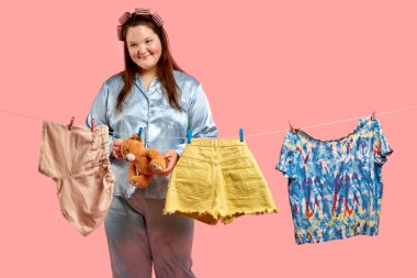 Pijamalı şişman bir kız çamaşırları yıkadıktan sonra asar, ev işleri yapar..